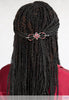 Intricate four petal flower with burgundy accents shown in black braids